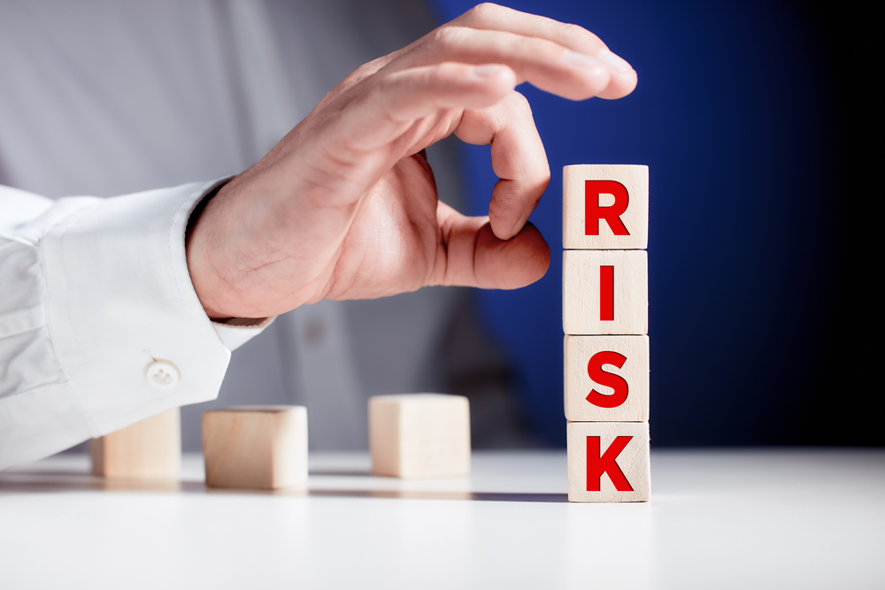 Image of a man about to topple over lettered blocks spelling the word Risk