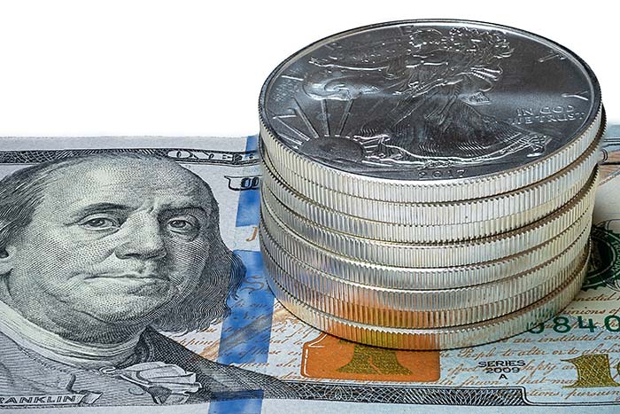Image of silver coins on top of a dollar bill